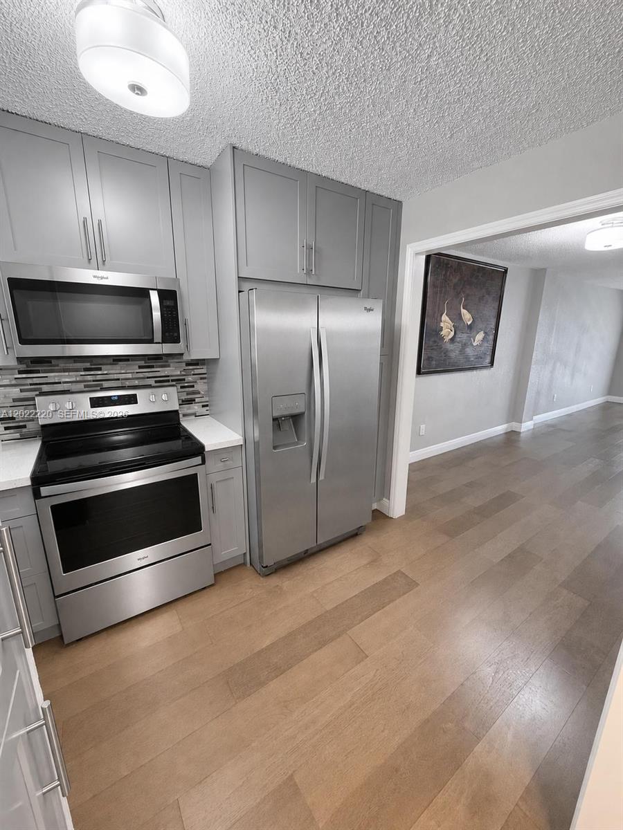 A kitchen with gray cabinets, stainless steel appliances, and wood-look flooring — 1635 W 44th Pl # 311, Hialeah FL 33012, HIALEAH, FL
