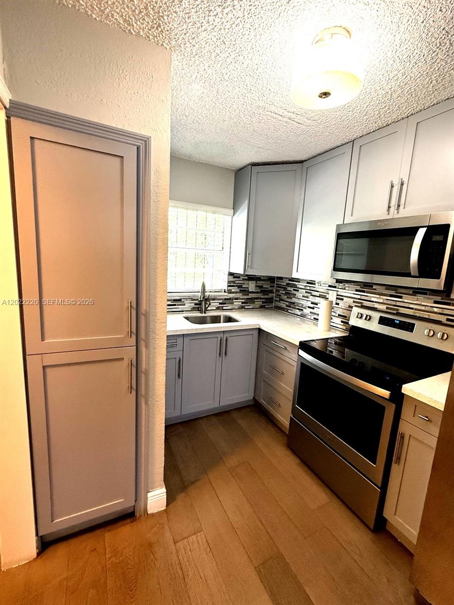 A kitchen features gray cabinets, stainless steel appliances, white countertops, and wood-look flooring — 1635 W 44th Pl # 311, Hialeah FL 33012, HIALEAH, FL