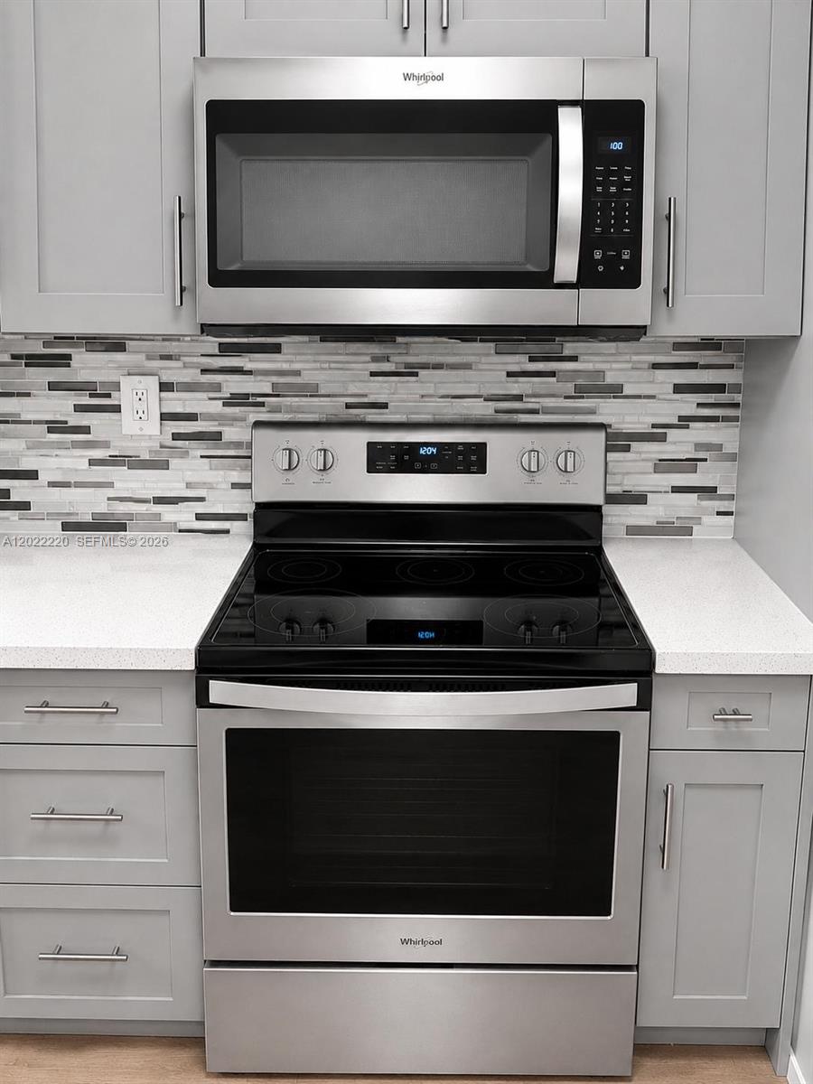 A stainless steel Whirlpool microwave and electric range are set between grey cabinets and countertops — 1635 W 44th Pl # 311, Hialeah FL 33012, HIALEAH, FL
