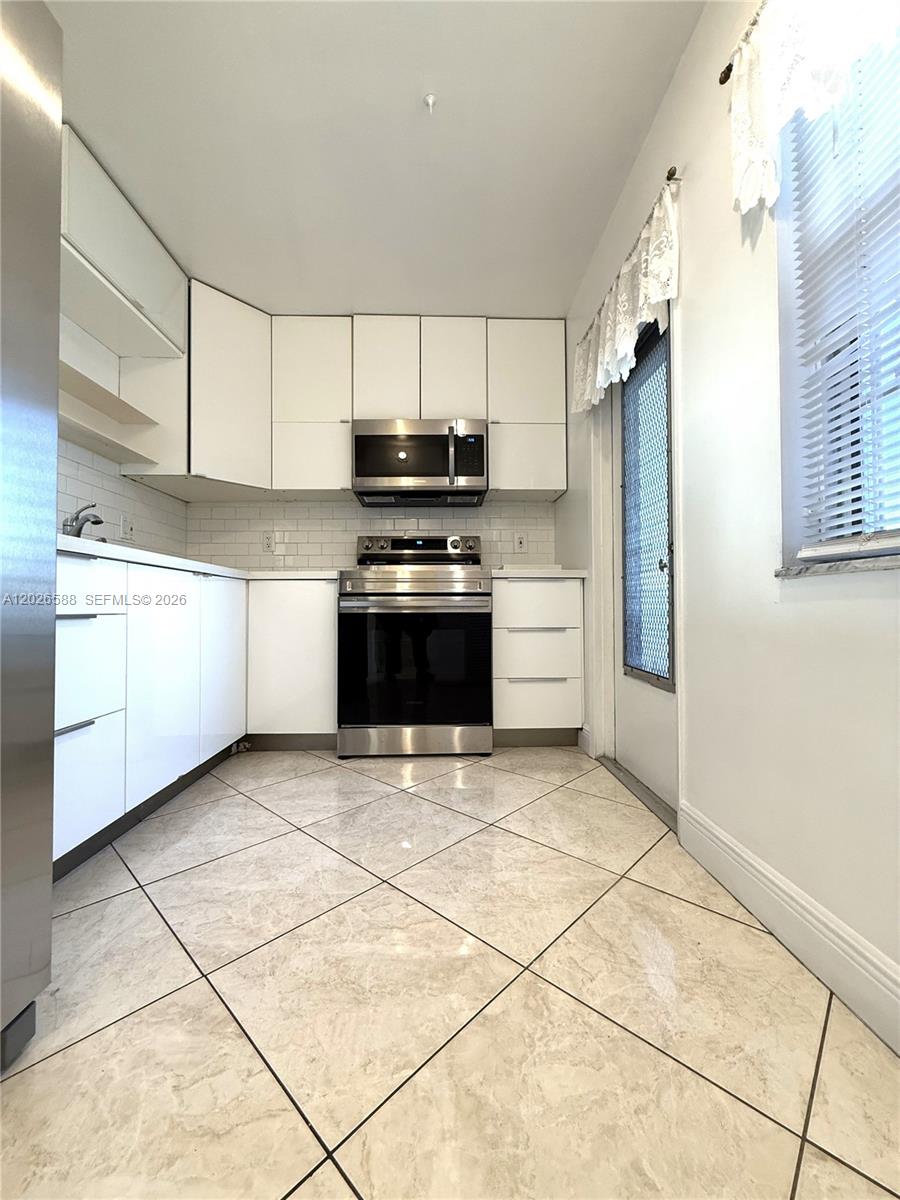 A kitchen features white flat-panel cabinets, stainless steel appliances, and light-colored tile flooring — 300 NE 14th Ave # 307, Hallandale Beach FL 33009, HALLANDALE BEACH, FL