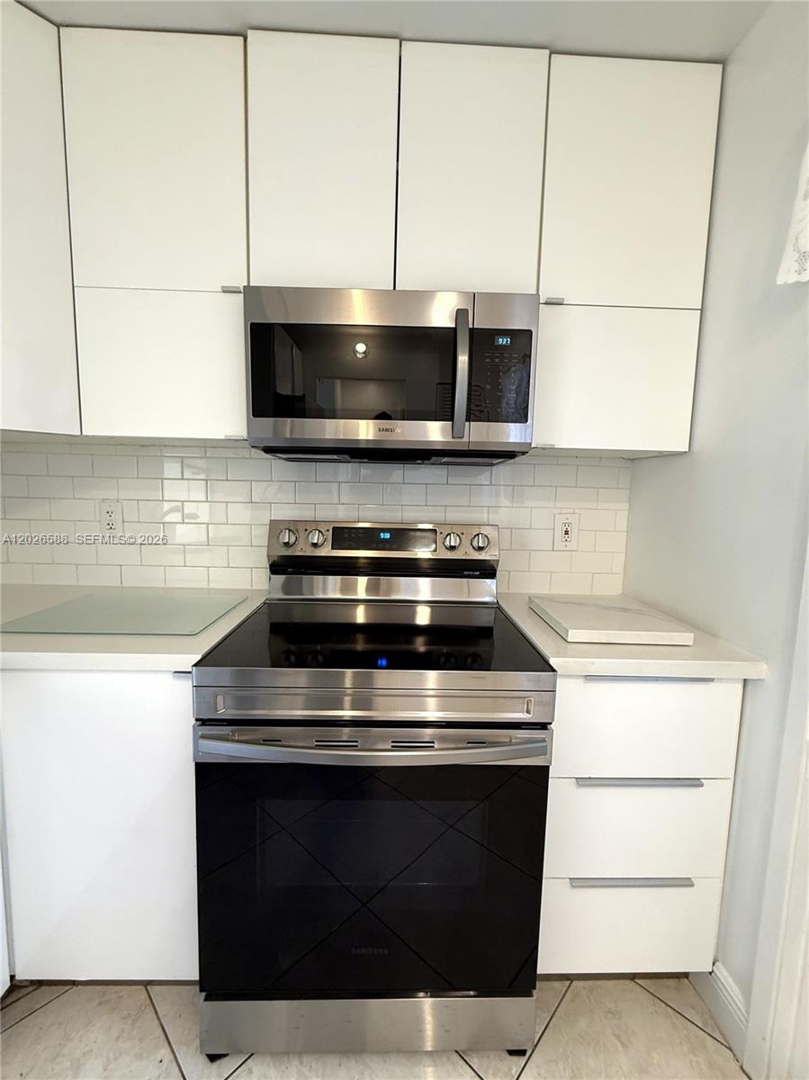 A kitchen features white cabinets, stainless steel appliances, and a white subway tile backsplash — 300 NE 14th Ave # 307, Hallandale Beach FL 33009, HALLANDALE BEACH, FL