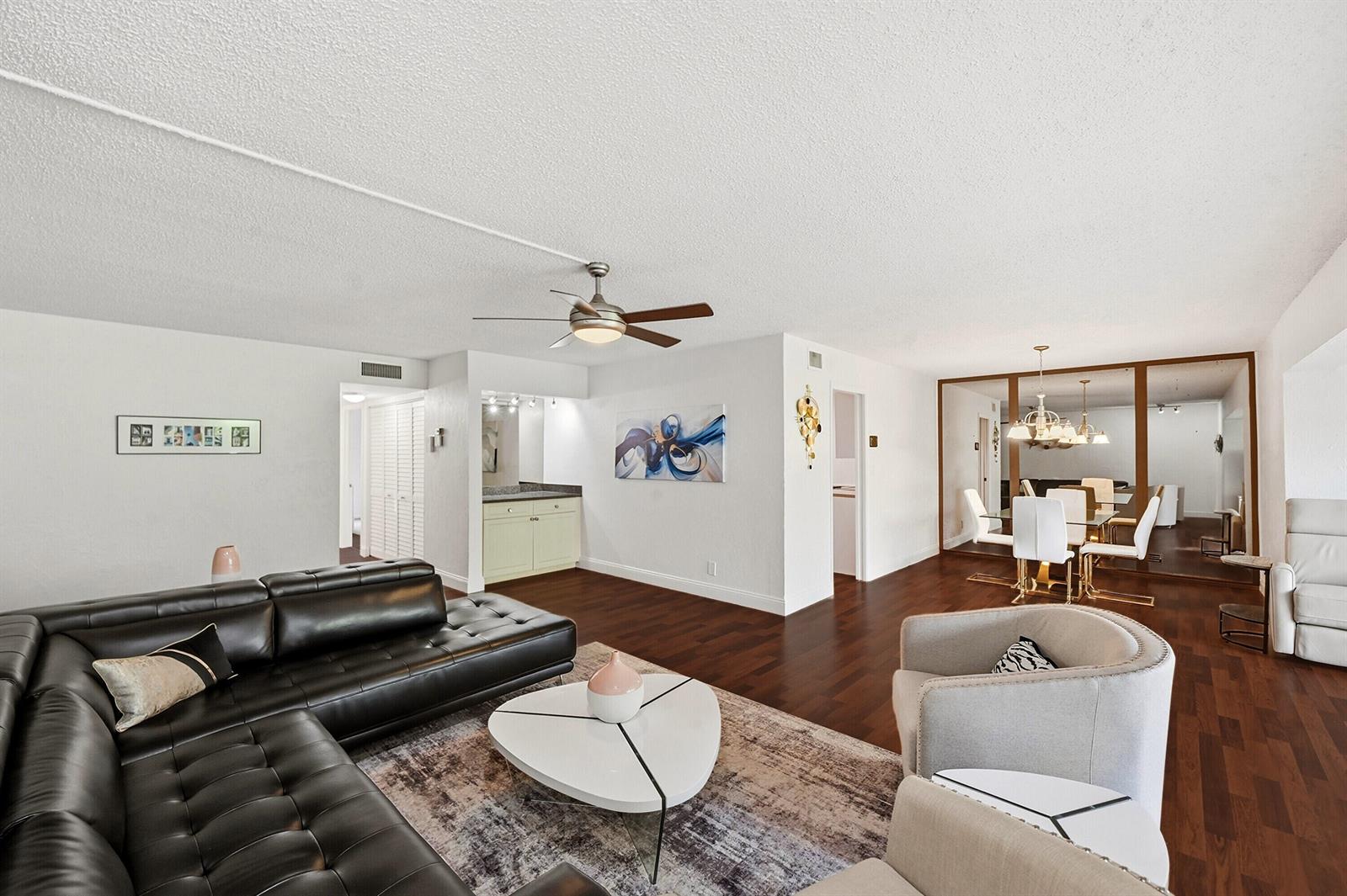 A living room with dark wood floors, a black leather sectional, and a dining area — 6612 Spring Bottom Way # 186, Boca Raton FL 33433, BOCA RATON, FL