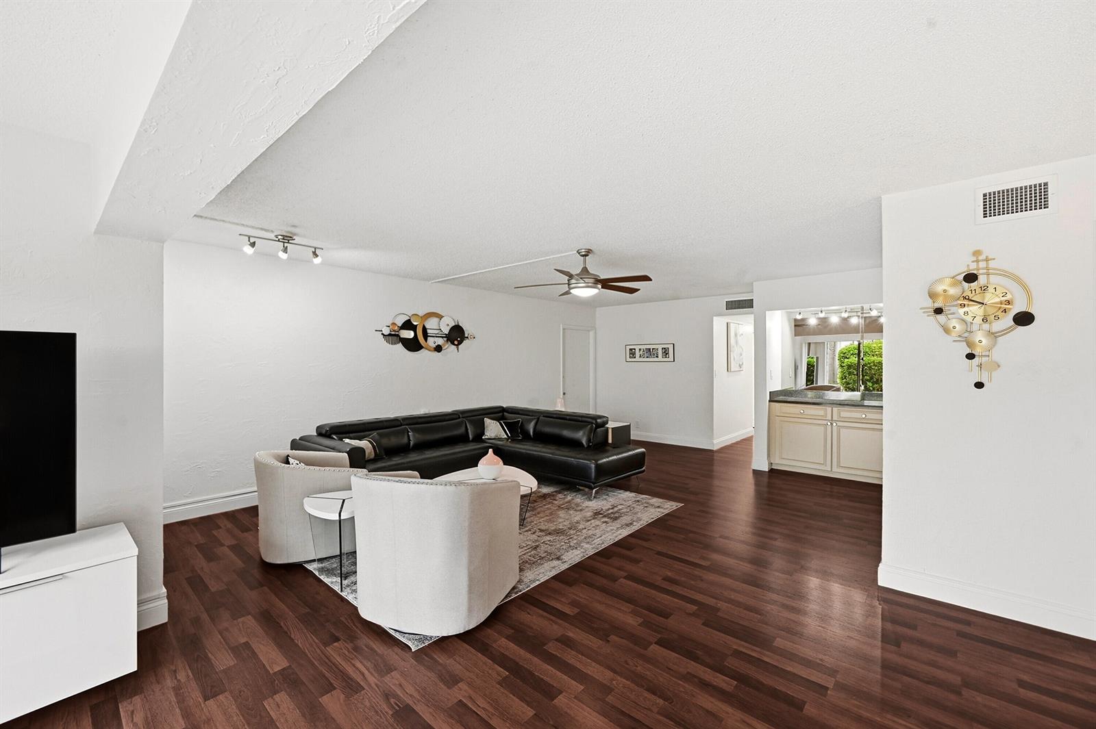 A living room features dark wood flooring, a black sectional sofa, and two cream armchairs — 6612 Spring Bottom Way # 186, Boca Raton FL 33433, BOCA RATON, FL