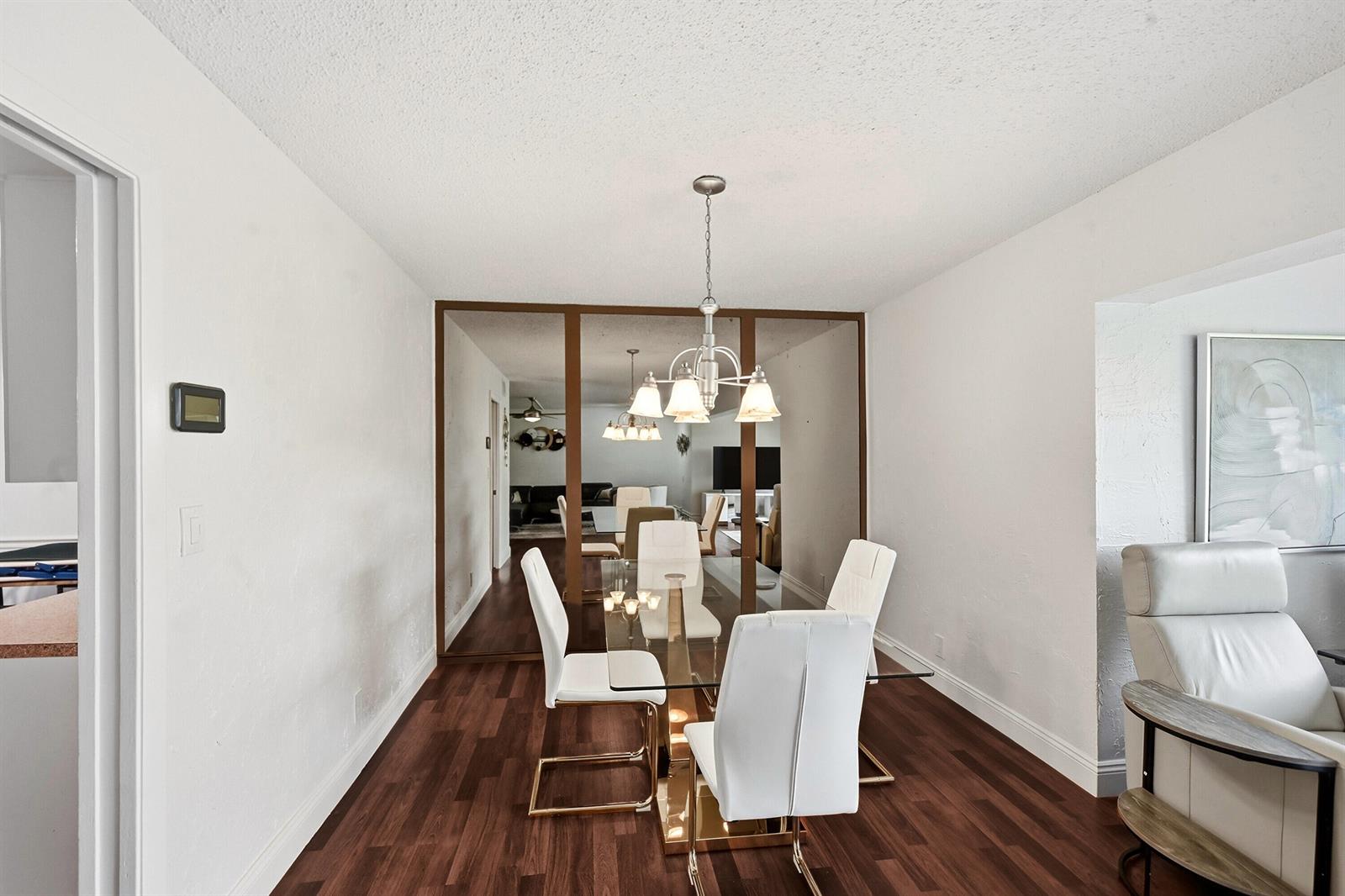 A dining room features a glass-top table, white chairs, dark wood flooring, and mirrored walls — 6612 Spring Bottom Way # 186, Boca Raton FL 33433, BOCA RATON, FL