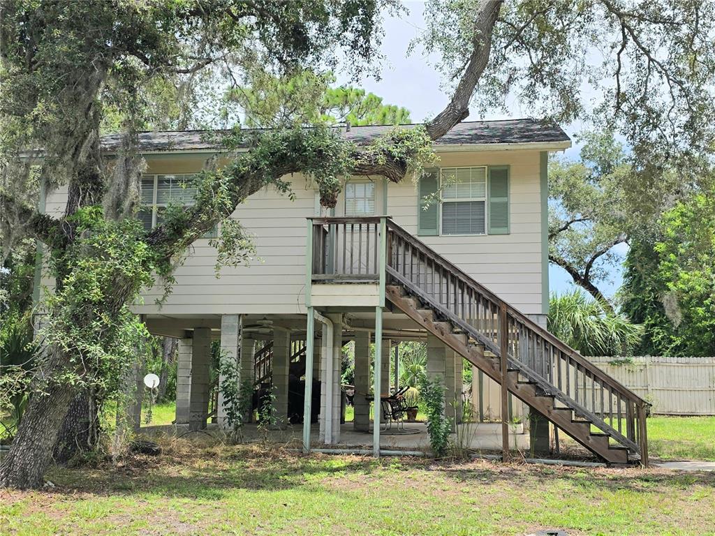 An elevated house with light siding, a wooden staircase, and a concrete block foundation — 14722 FAIR OAK WAY, HUDSON, FL