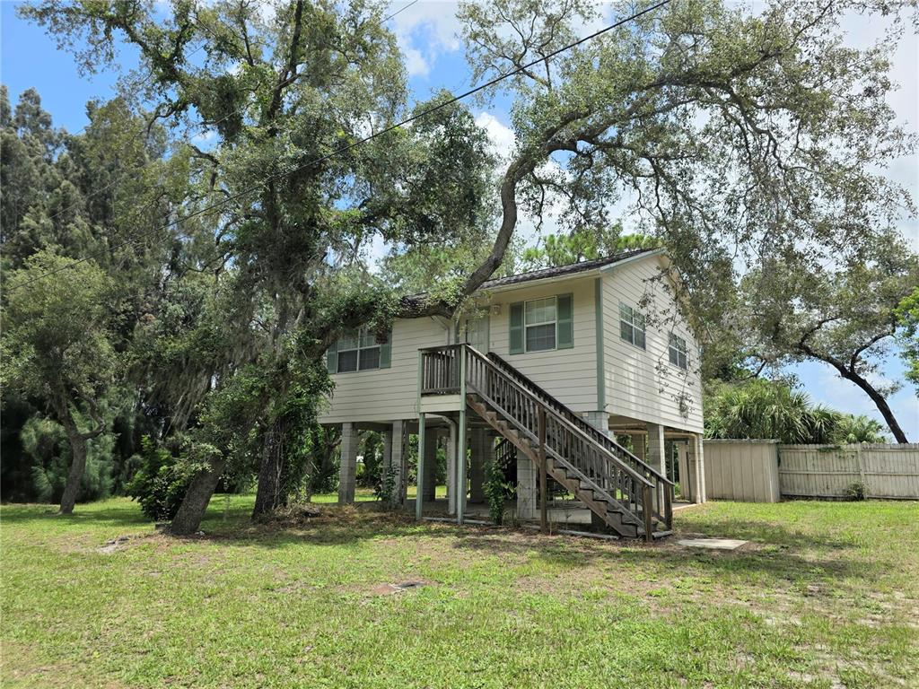 A two-story house on stilts features a wooden staircase leading to the elevated entrance — 14722 FAIR OAK WAY, HUDSON, FL