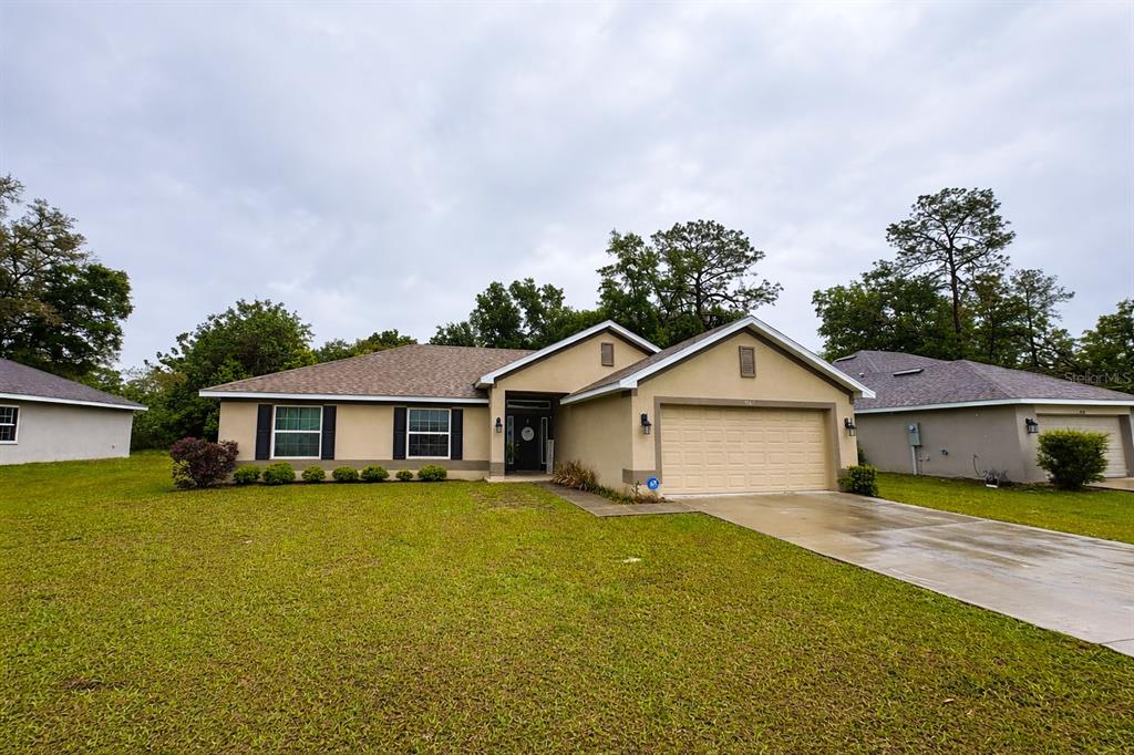 A single-story house with a tan exterior, a two-car garage, and a grassy front yard — 3962 NE 58TH CIRCLE, SILVER SPRINGS, FL