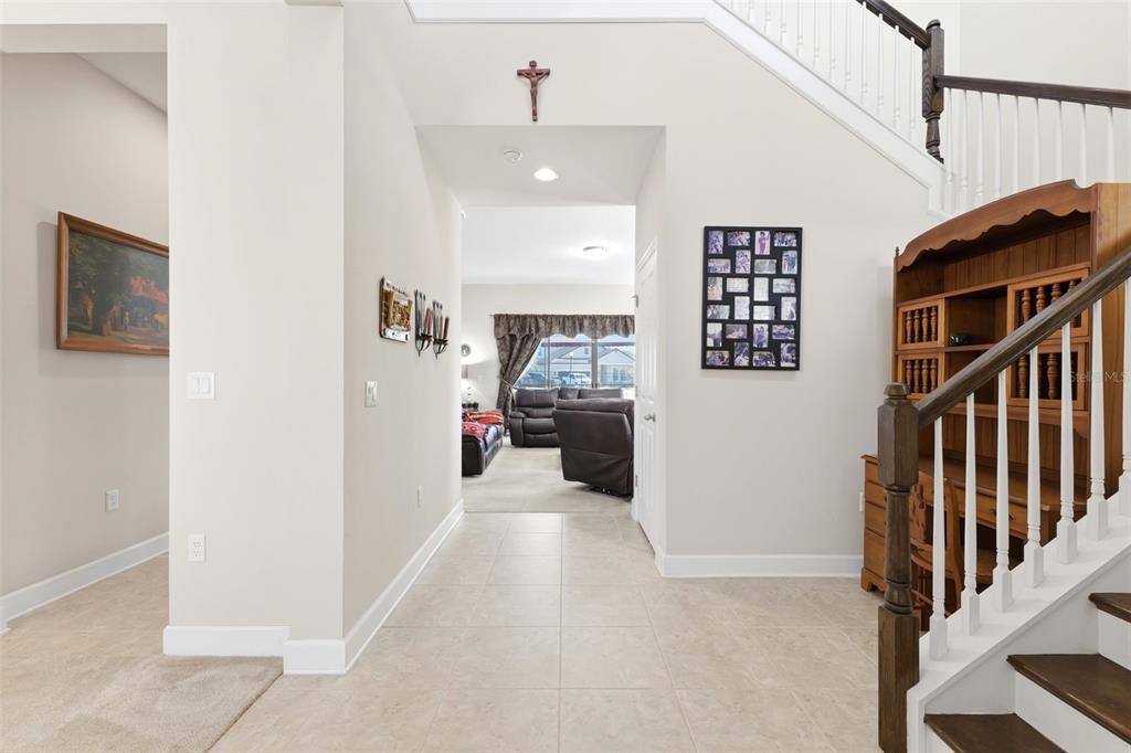 A tiled entryway leads to a living area with a staircase and wooden hutch — 4924 BUTLER NATIONAL DRIVE, WESLEY CHAPEL, FL