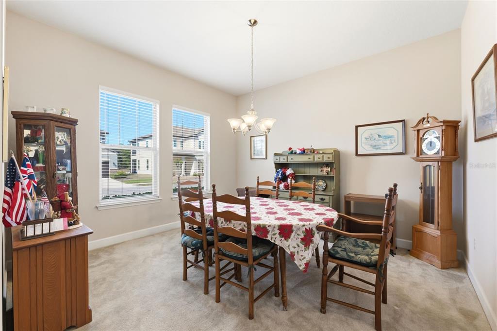 A dining room features a round table with chairs, a hutch, and a grandfather clock — 4924 BUTLER NATIONAL DRIVE, WESLEY CHAPEL, FL
