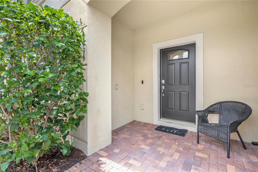 A front entryway features a dark door, a wicker chair, and a brick-paved porch — 1995 MAJORCA DRIVE, KISSIMMEE, FL