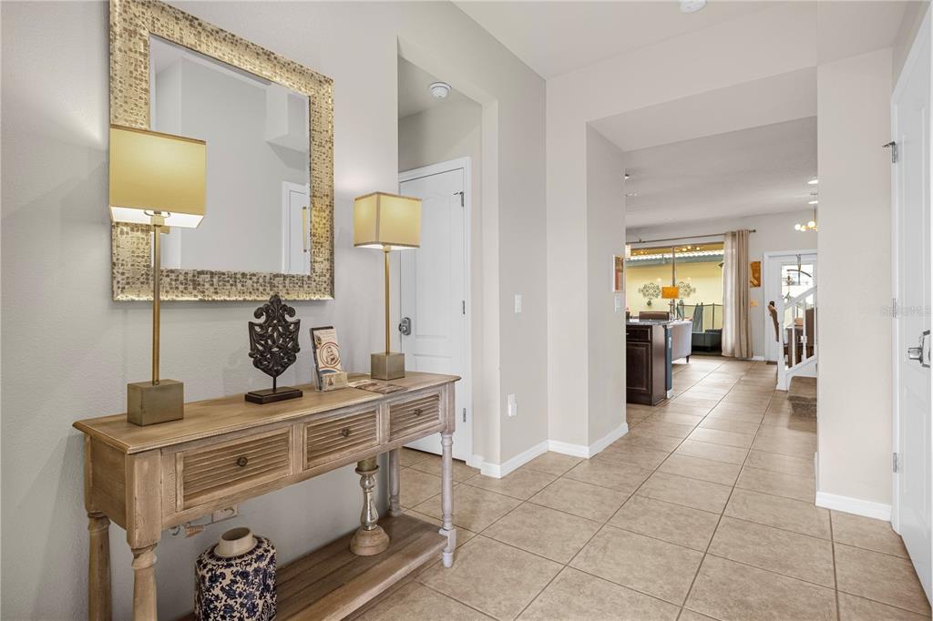 A tiled entryway features a wooden console table with lamps and a mirror on the wall — 1995 MAJORCA DRIVE, KISSIMMEE, FL