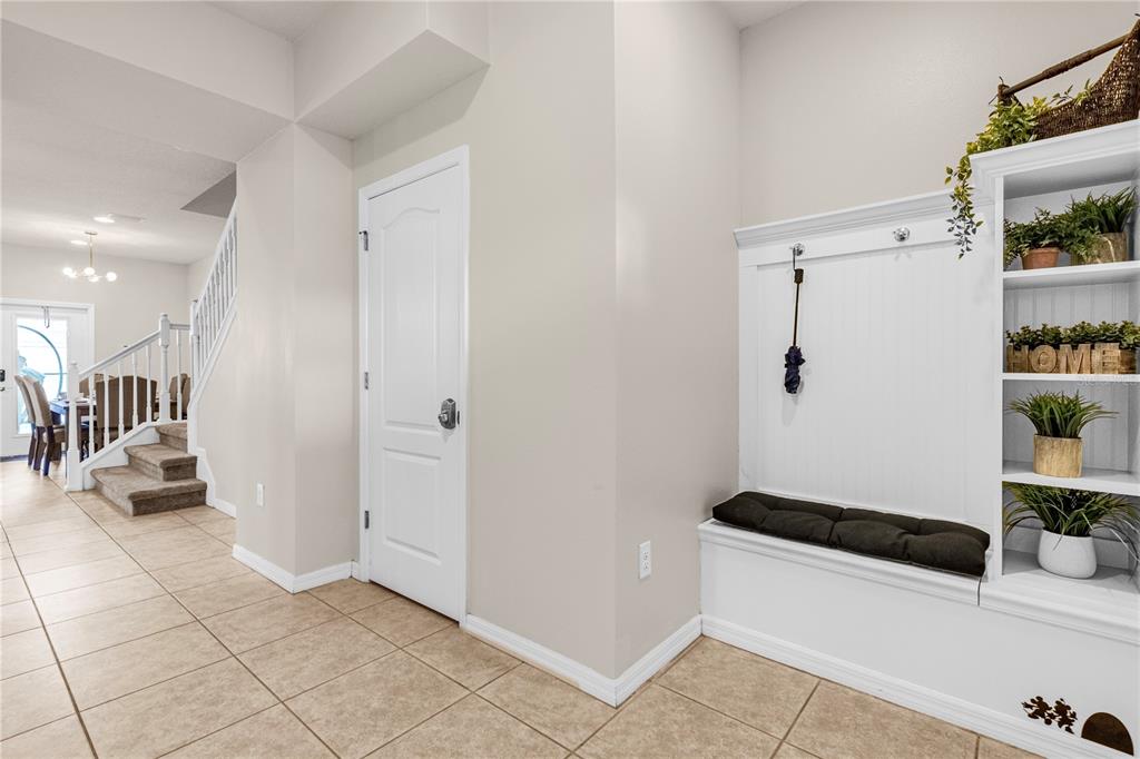 A tiled entryway features a white built-in bench with shelving and a staircase nearby — 1995 MAJORCA DRIVE, KISSIMMEE, FL