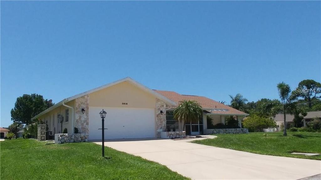 A single-story house with a two-car garage, stone accents, and a paved driveway — 5816 MONROE ROAD, VENICE, FL