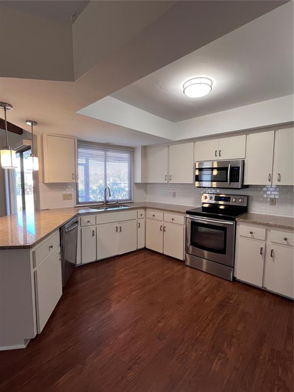 A kitchen with white cabinets, stainless steel appliances, granite countertops, and wood-look flooring — 5816 MONROE ROAD, VENICE, FL