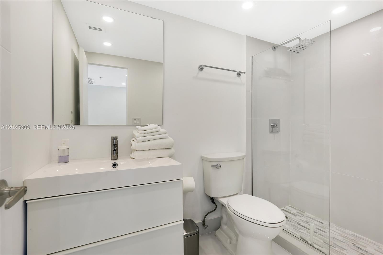 A modern bathroom features a white vanity, a glass-enclosed shower, and a toilet — 5445 Collins Ave # 928, Miami Beach FL 33140, MIAMI BEACH, FL
