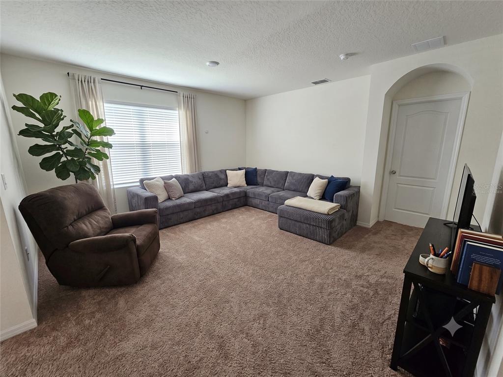 A living room features a large gray sectional, a brown recliner, and beige carpeting — 231 WILLOW BEND DRIVE, DAVENPORT, FL