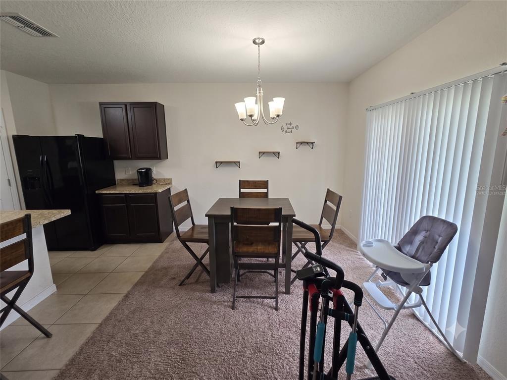 A dining area features a dark wood table and chairs, a chandelier, and tile flooring — 231 WILLOW BEND DRIVE, DAVENPORT, FL