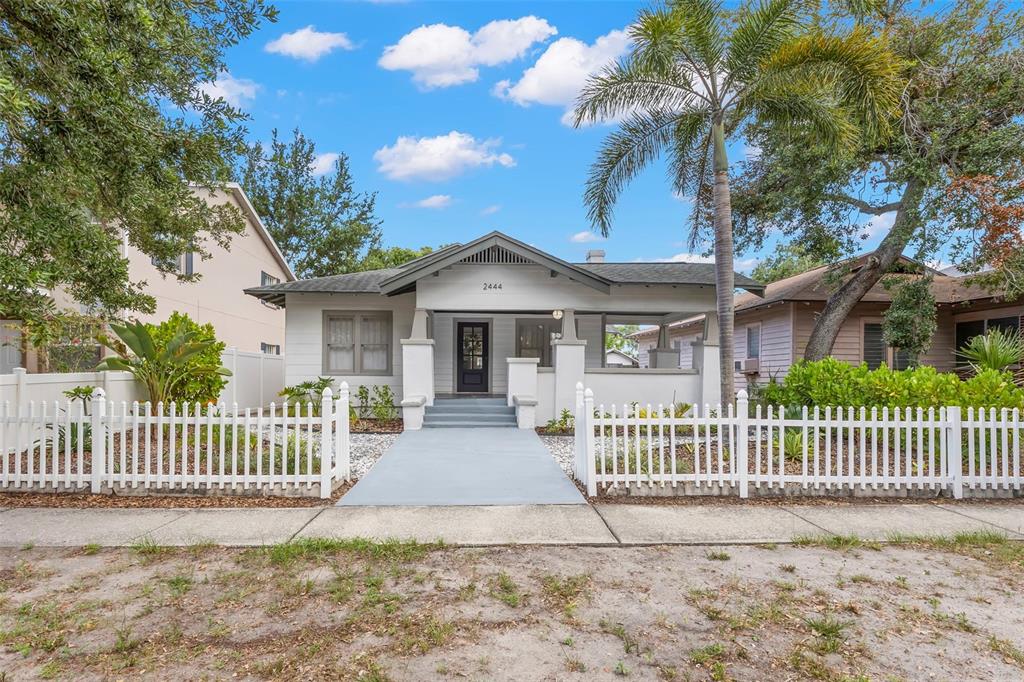 A white bungalow with a front porch and a white picket fence under a blue sky — 2444 1ST AVENUE S, ST PETERSBURG, FL