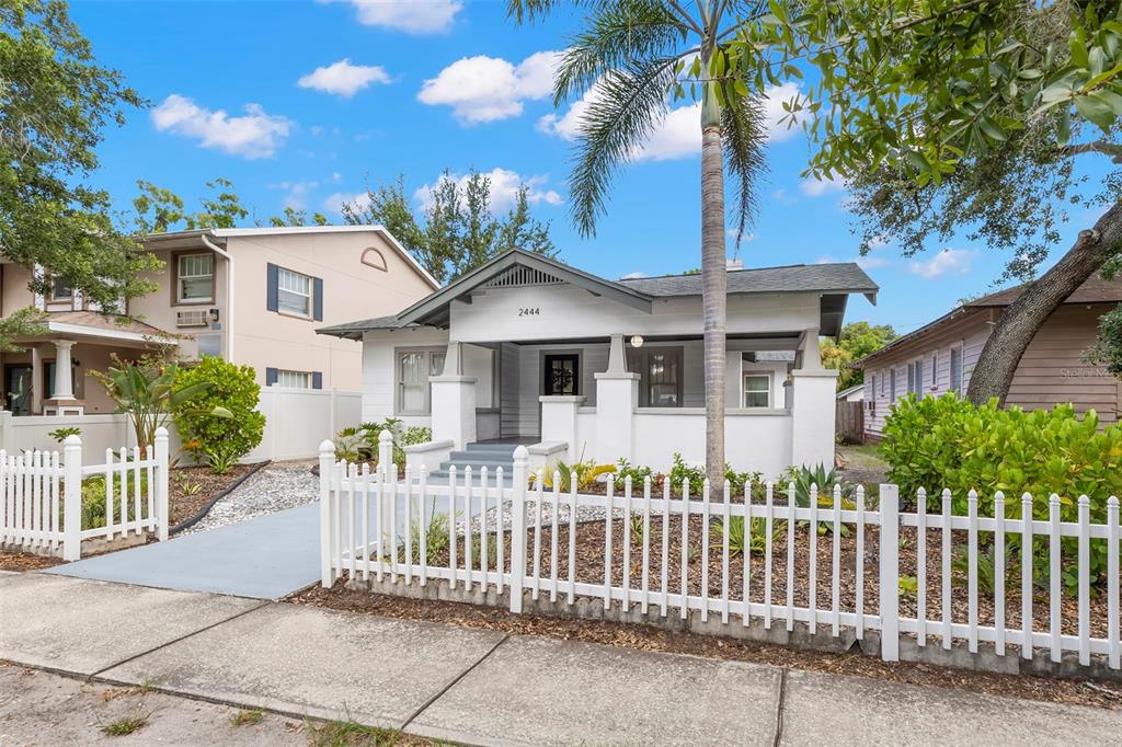 A white bungalow with a front porch and a white picket fence under a blue sky — 2444 1ST AVENUE S, ST PETERSBURG, FL
