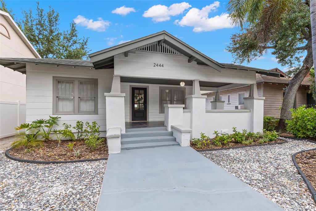 A white bungalow with a front porch, gray steps, and a gravel yard — 2444 1ST AVENUE S, ST PETERSBURG, FL