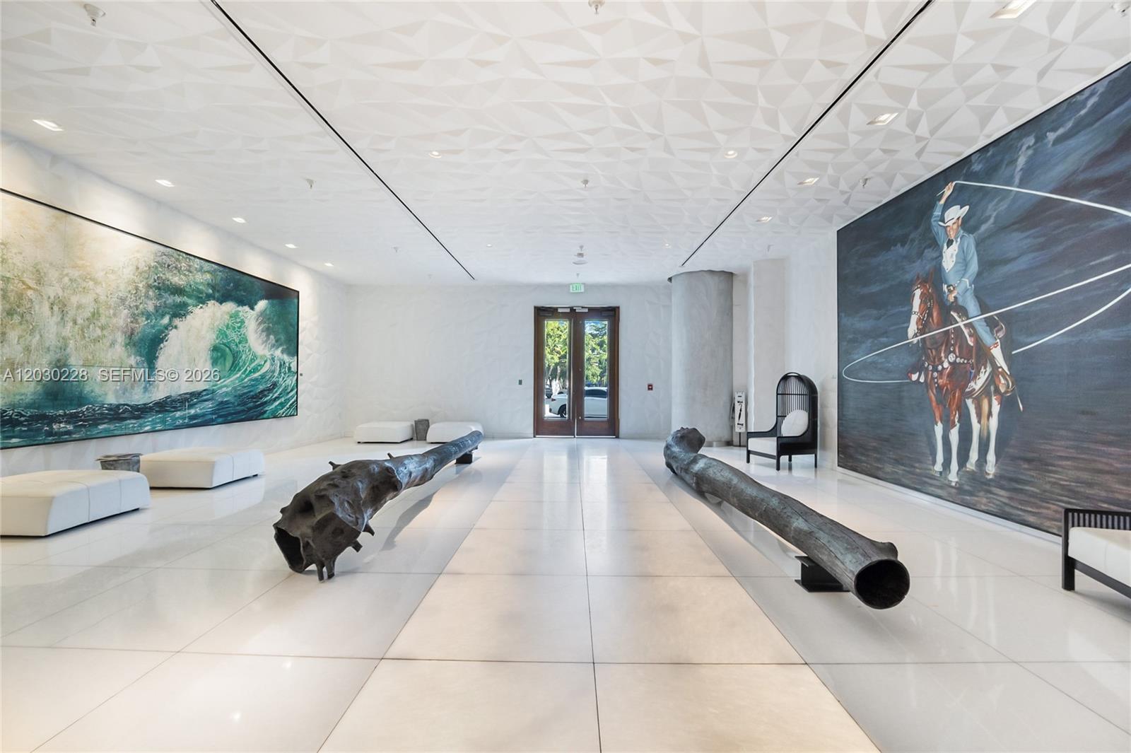 A modern lobby features white tiled floors, geometric ceiling panels, two large sculptures, and wall art — 1300 S Miami Ave # 1705, Miami FL 33130, MIAMI, FL