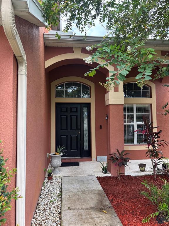 The exterior of a house features a black front door, arched entryway, and red mulch — 11153 SHELTER COVE LOOP, NEW PORT RICHEY, FL