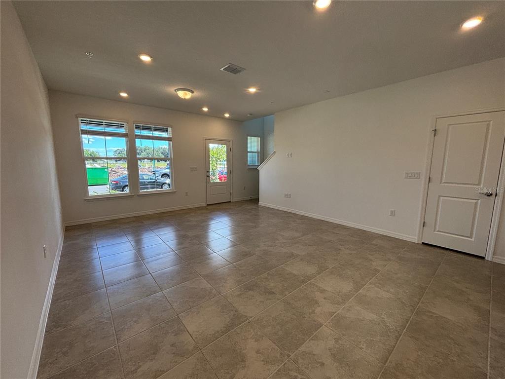 An open-concept living area features light-colored tile flooring, recessed lighting, and large windows — 11451 HARBORVIEW STREET, ORLANDO, FL
