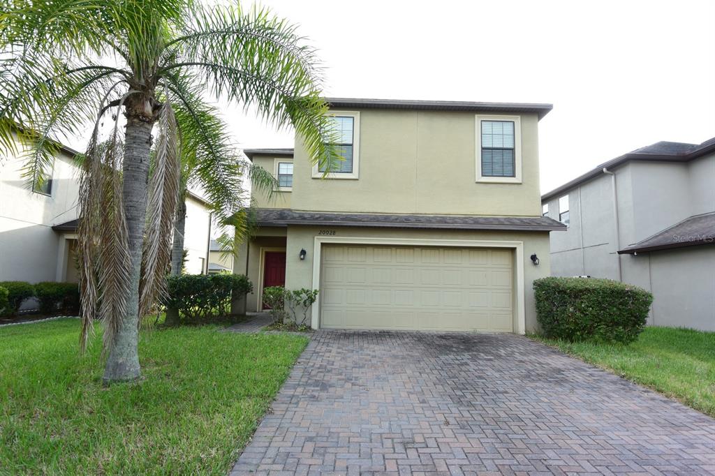 A two-story house with a beige stucco exterior, a two-car garage, and a palm tree — 20028 SATIN LEAF AVENUE, TAMPA, FL