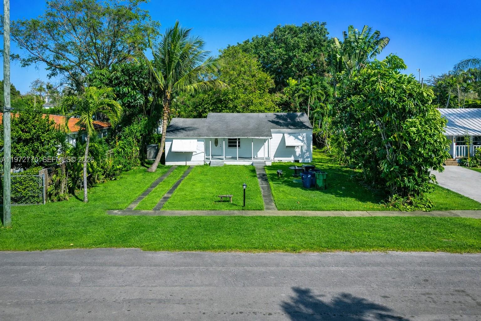 A white single-story house with a front porch sits behind a grassy yard — 10821 NE 5th Ave, Miami FL 33161, MIAMI, FL