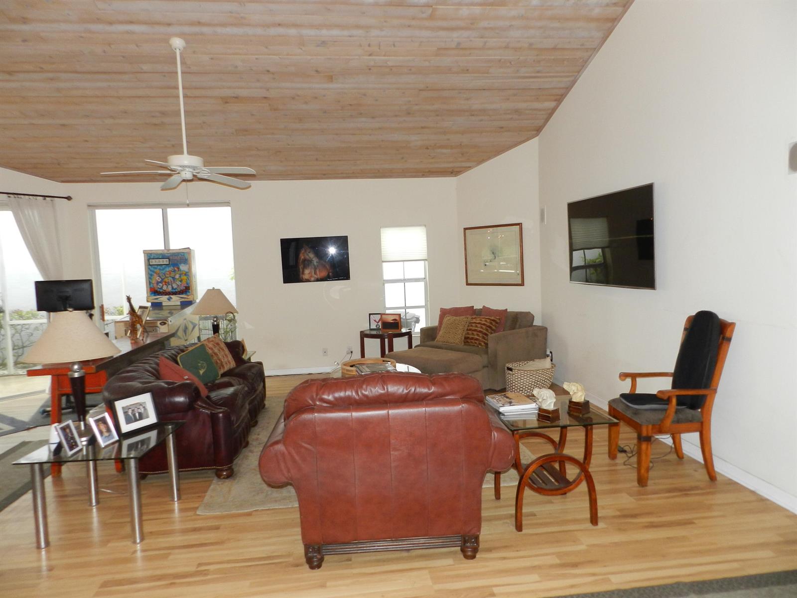 A living room features a vaulted wood-plank ceiling, leather furniture, and a wall-mounted television — 9198 Heathridge Drive, West Palm Beach FL 33411, WEST PALM BEACH, FL