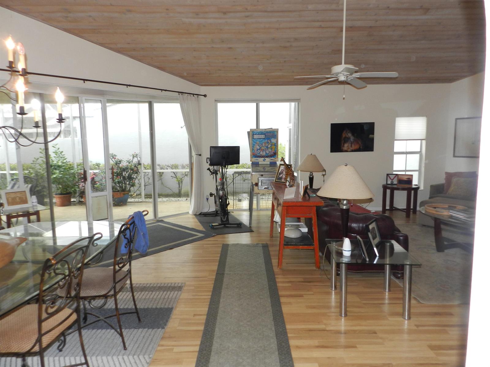 A living and dining area features wood-paneled ceilings, hardwood floors, and sliding glass patio doors — 9198 Heathridge Drive, West Palm Beach FL 33411, WEST PALM BEACH, FL