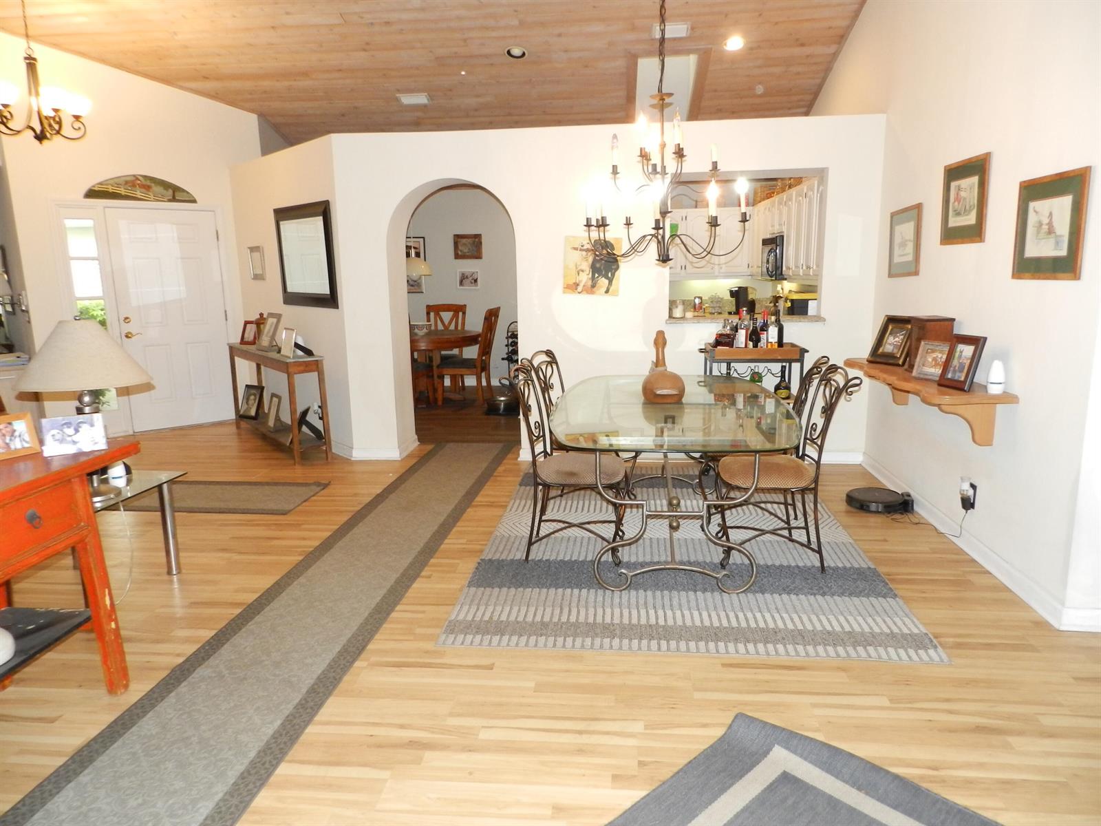 A dining area with a glass table, chandelier, and arched doorway leading to another room — 9198 Heathridge Drive, West Palm Beach FL 33411, WEST PALM BEACH, FL