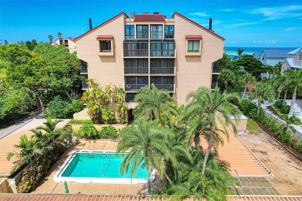 An exterior view of a multi-story apartment building with a swimming pool and palm trees — 4900 OCEAN BOULEVARD UNIT 501, SARASOTA, FL