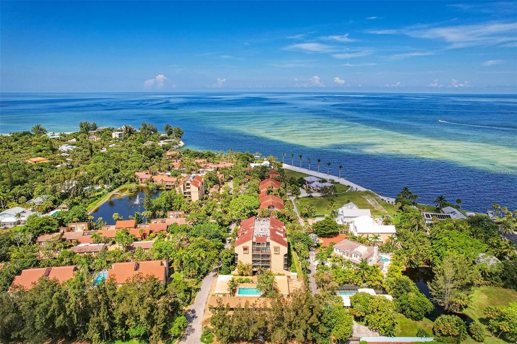 An aerial view of a coastal residential complex with multiple buildings, a pond, and oceanfront access — 4900 OCEAN BOULEVARD UNIT 501, SARASOTA, FL