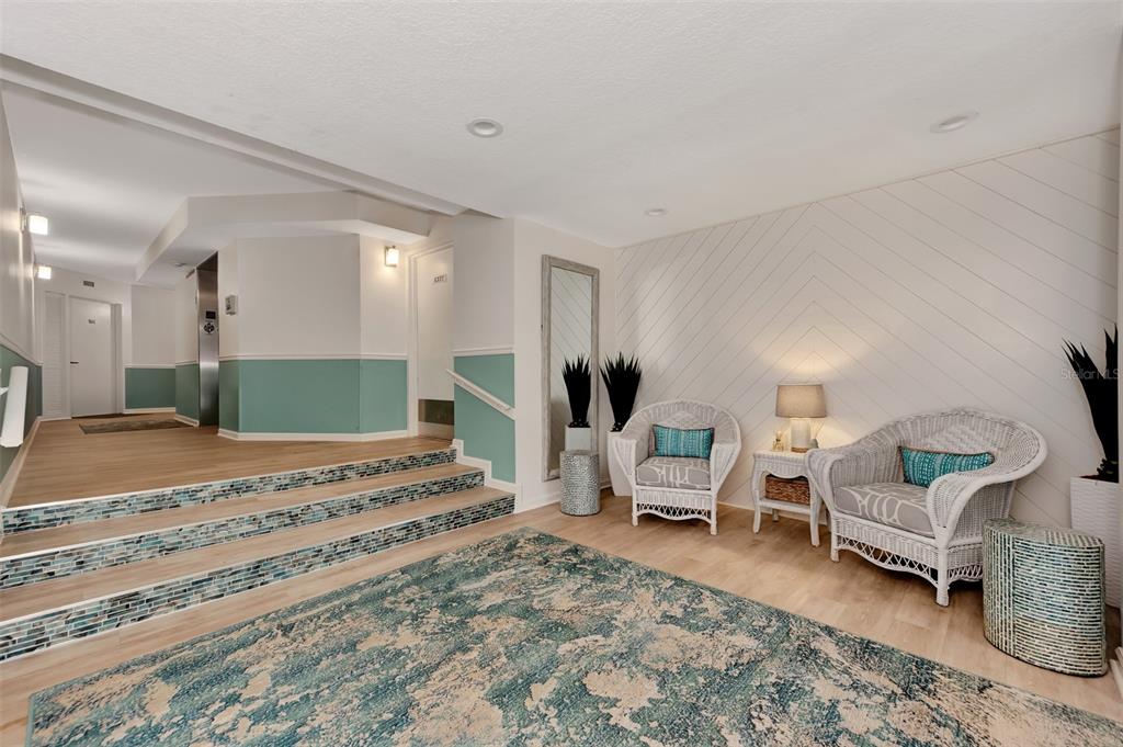 A lobby features two white wicker chairs, a patterned rug, and stairs with tiled risers — 4900 OCEAN BOULEVARD UNIT 501, SARASOTA, FL