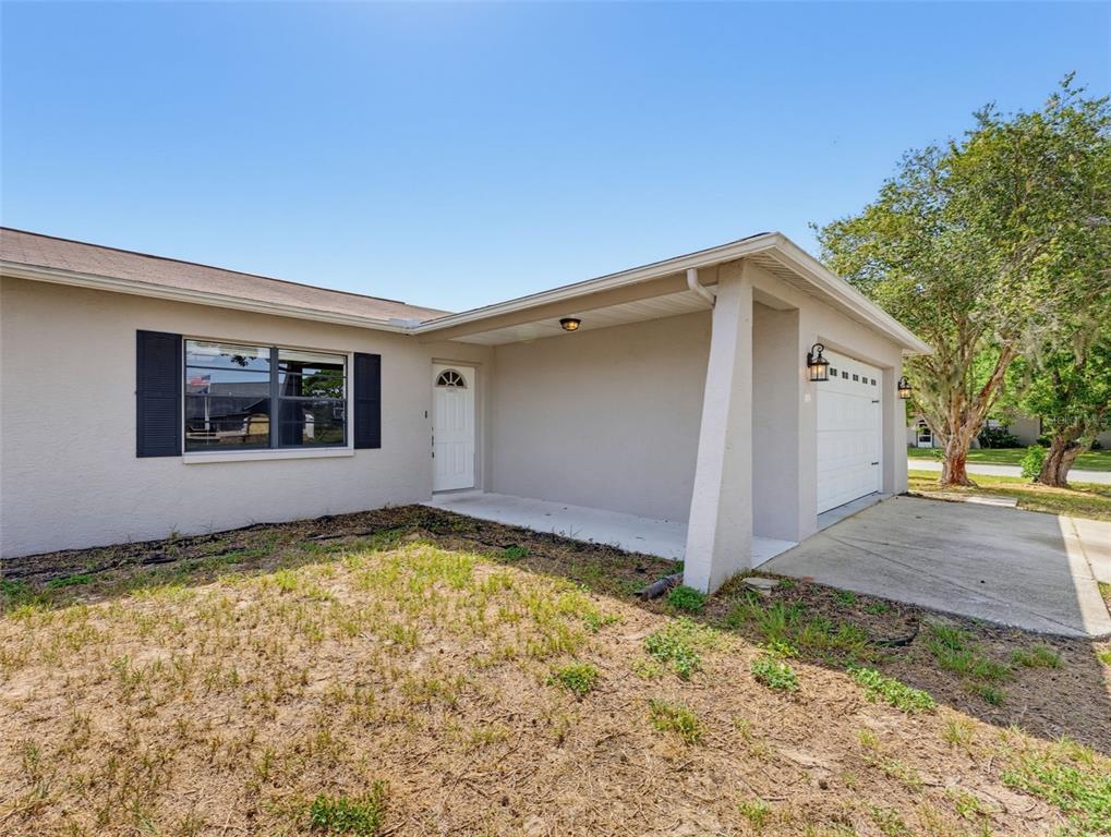 A single-story house exterior features a beige stucco facade, a garage, and a front porch — 4526 BAYRIDGE COURT, SPRING HILL, FL