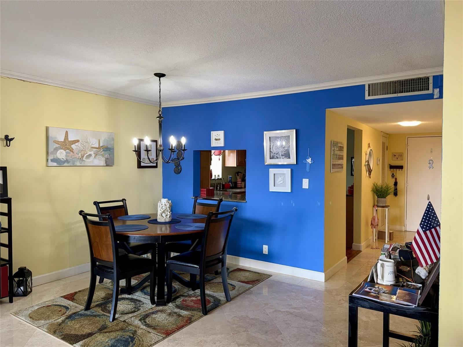 A dining area features a round wooden table, four chairs, and bold yellow and blue walls — 2304 S Cypress Bend Drive # 615, Pompano Beach FL 33069, POMPANO BEACH, FL