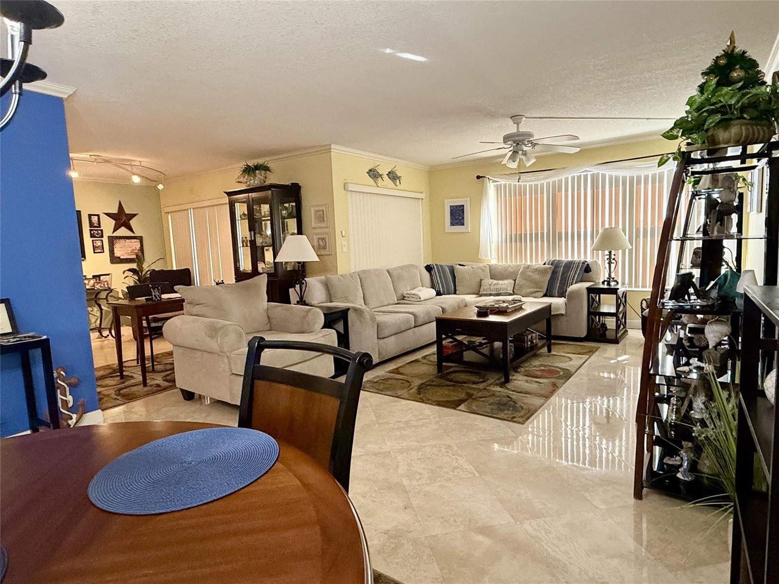A spacious living room features light-colored tile flooring, a large sectional sofa, and a ceiling fan — 2304 S Cypress Bend Drive # 615, Pompano Beach FL 33069, POMPANO BEACH, FL