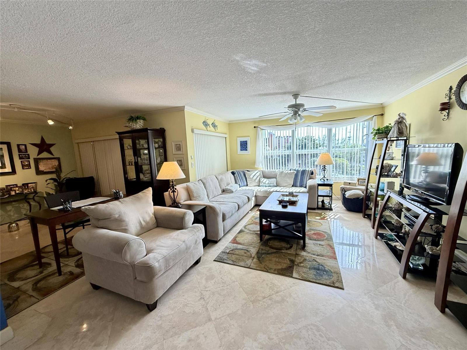 A living room features light-colored tile floors, a sectional sofa, and a ceiling fan — 2304 S Cypress Bend Drive # 615, Pompano Beach FL 33069, POMPANO BEACH, FL