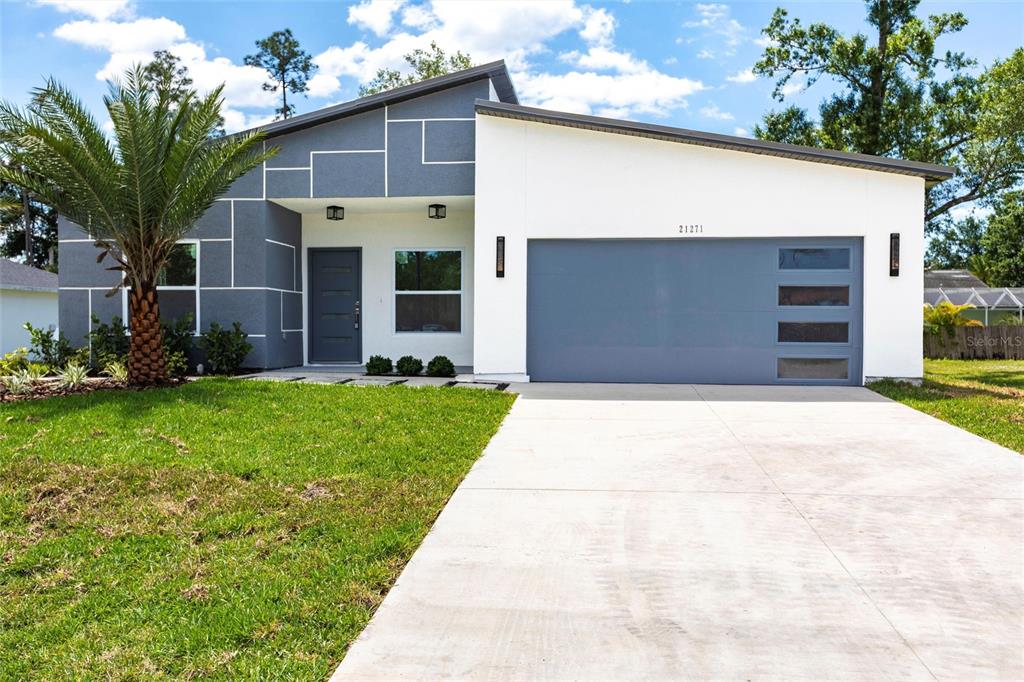 A modern single-story house features a gray and white exterior with a two-car garage — 12123 PLATANO DRIVE, PUNTA GORDA, FL