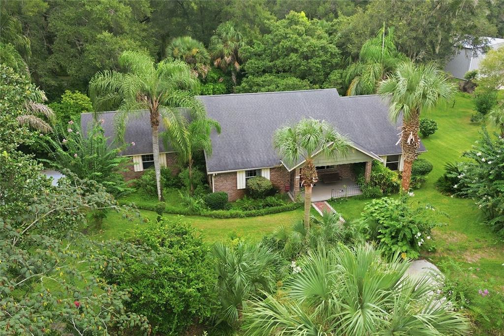 An aerial view of a brick house with a gray roof surrounded by lush trees — 1925 LADY BUG LANE, DELAND, FL