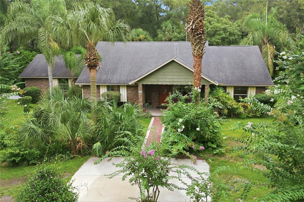 A brick house with a green gable roof and a brick walkway leading to the entrance — 1925 LADY BUG LANE, DELAND, FL