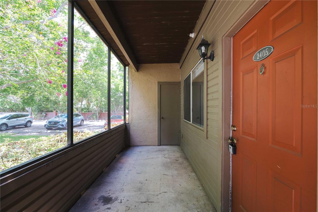 A screened-in porch features a concrete floor, a brown door, and a view of cars — 10263 GANDY BOULEVARD N UNIT 2405, ST PETERSBURG, FL