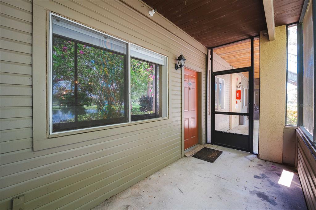 A covered outdoor entryway features a concrete floor, a red door, and a screened enclosure — 10263 GANDY BOULEVARD N UNIT 2405, ST PETERSBURG, FL
