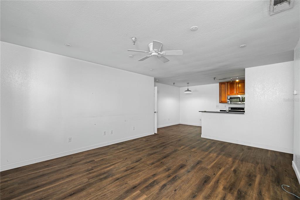 An open-concept living area with white walls, wood-look flooring, a ceiling fan, and a kitchen — 10263 GANDY BOULEVARD N UNIT 2405, ST PETERSBURG, FL