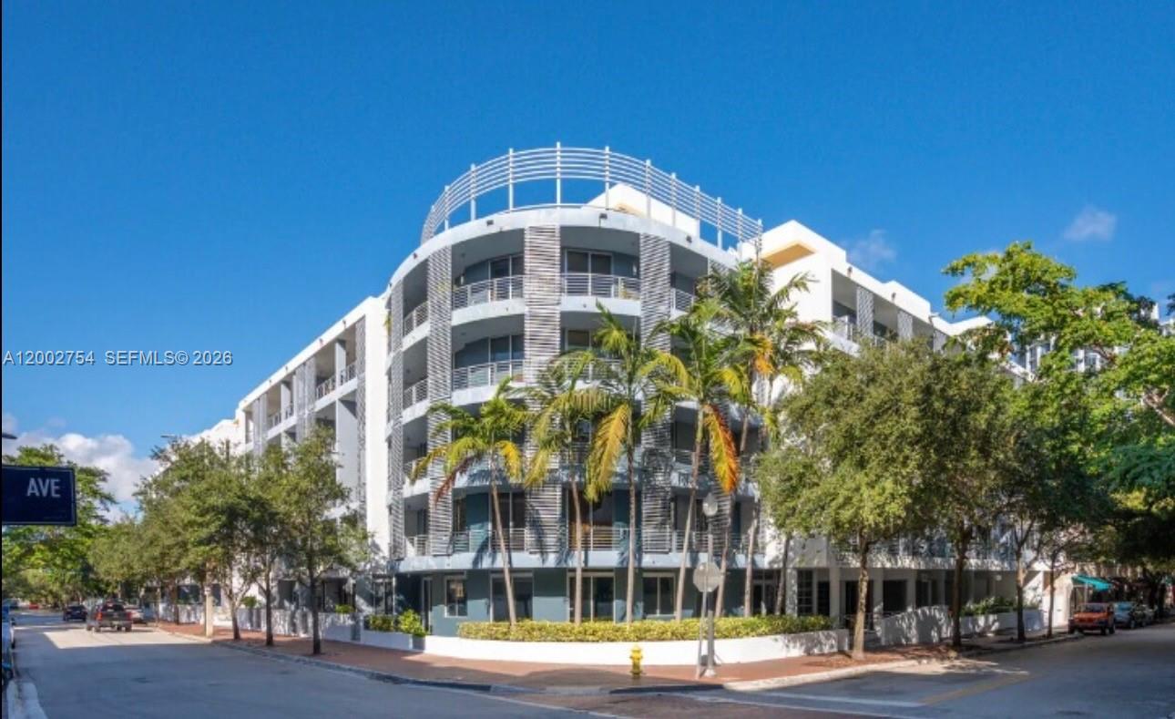 A multi-story apartment building with a curved facade and balconies stands on a street corner — 3339 Virginia St # 127, Miami FL 33133, MIAMI, FL