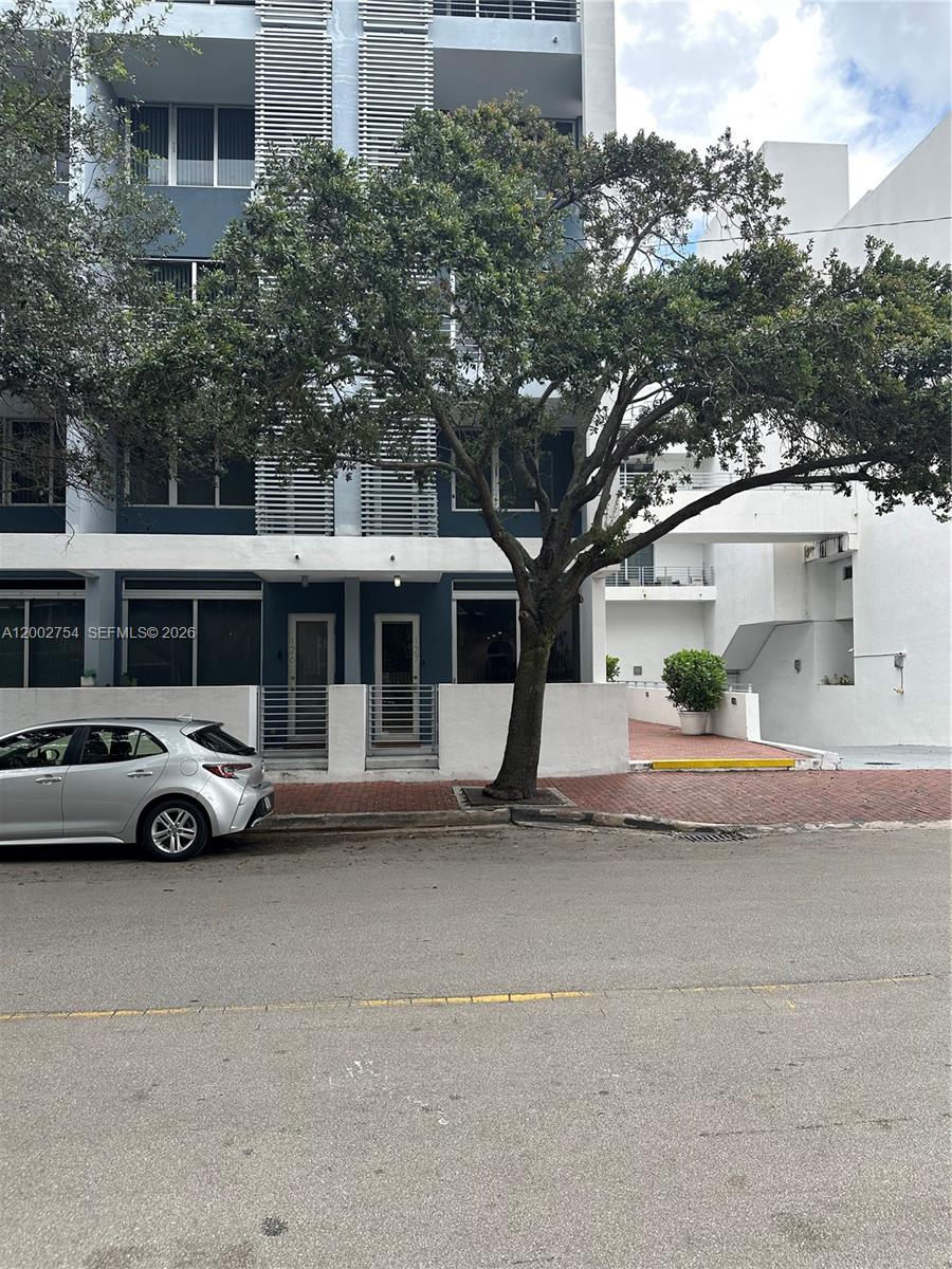 A silver hatchback is parked in front of a modern multi-story building with trees — 3339 Virginia St # 127, Miami FL 33133, MIAMI, FL