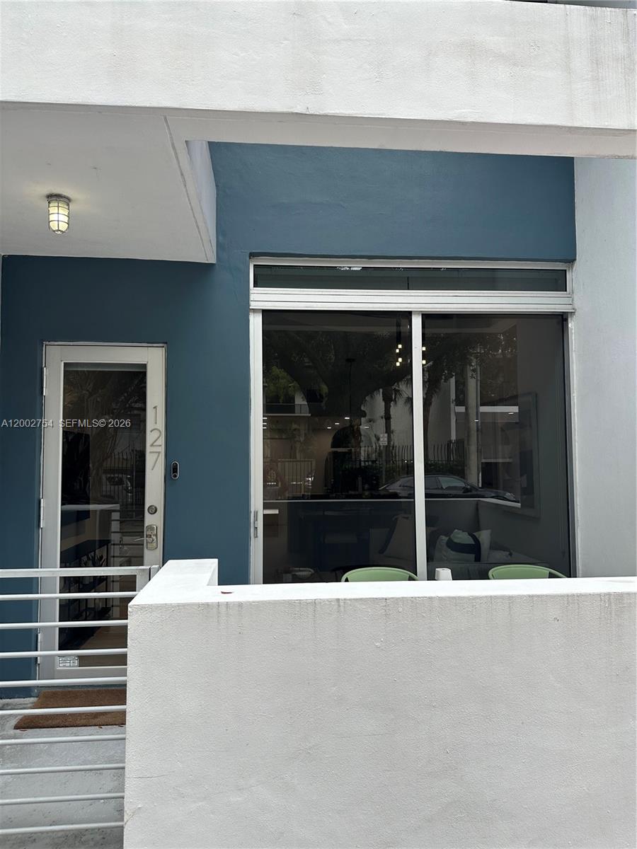 The exterior of a building features a blue wall, a glass door, and a large window — 3339 Virginia St # 127, Miami FL 33133, MIAMI, FL