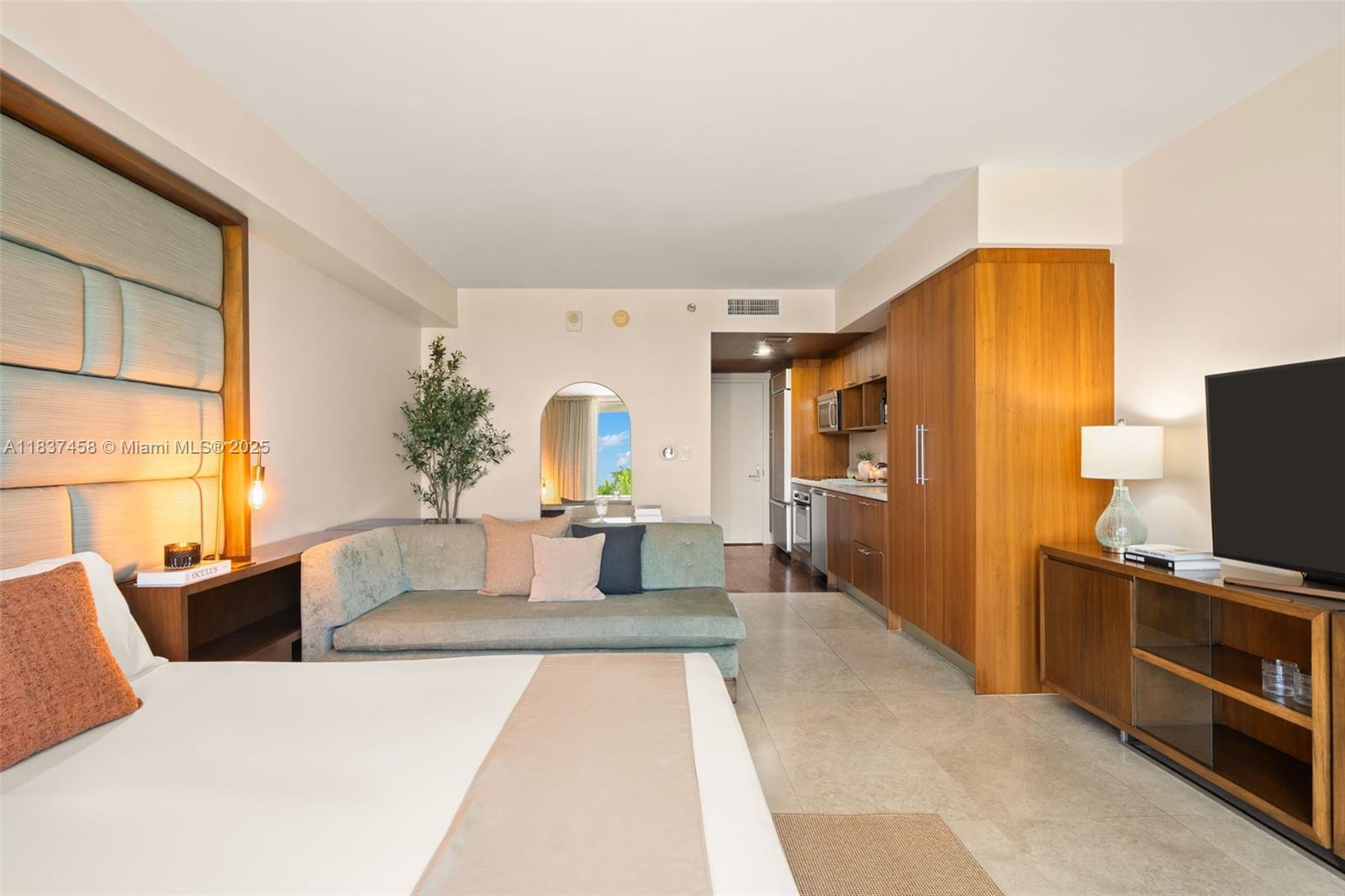 A hotel-style studio room features a bed, a sofa, a kitchenette, and a television console — 50 Biscayne Blvd # 411, Miami FL 33132, MIAMI, FL