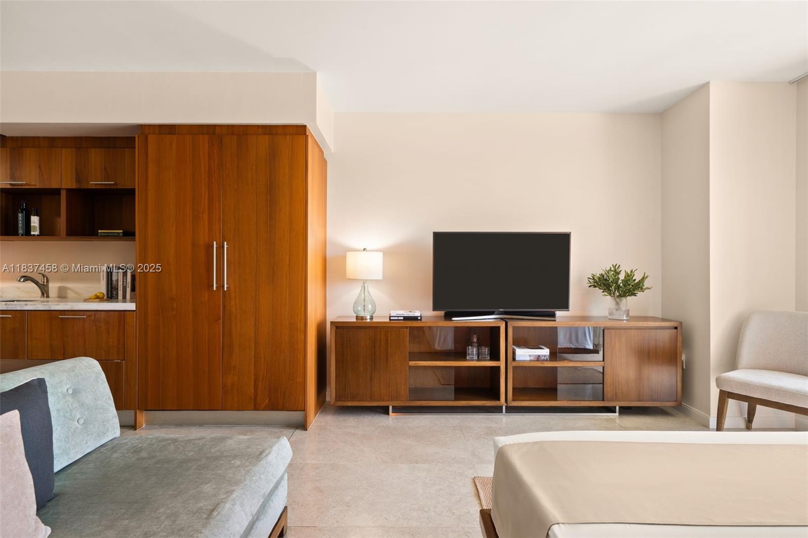A living room features a wooden cabinet, a television on a media console, and furniture — 50 Biscayne Blvd # 411, Miami FL 33132, MIAMI, FL